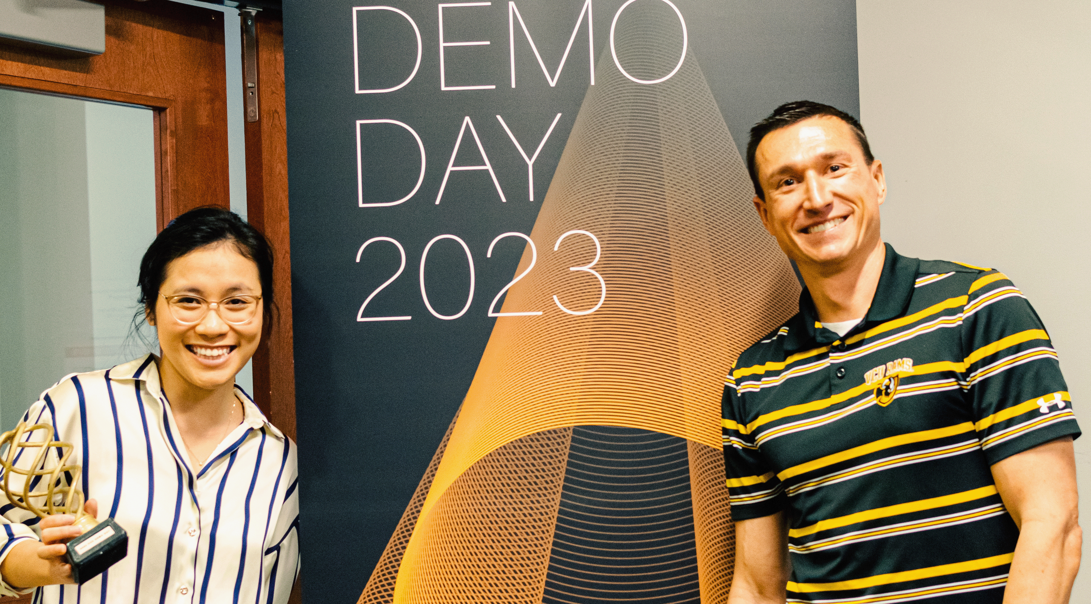 Garret Westlake, Ph.D., with an awardee from Demo Day 2023, in front of a banner with the the text, 